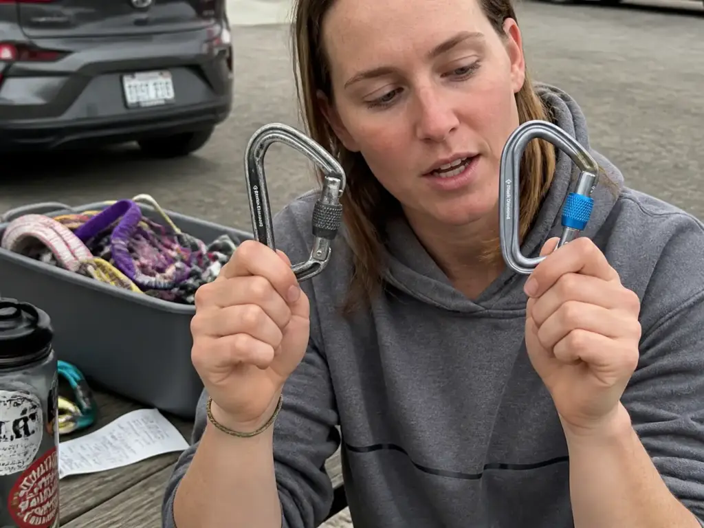 Budget screwgate locking carabiner held beside a premium locker showing both carry the same certification