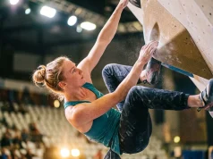 7 Best Climbing Documentaries About Competitions Ranked Female competition climber executing a difficult bat-hang move on fiberglass volumes