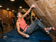 Climbing Gyms in LA That Are Actually Worth It Climber on bouldering wall at Los Angeles climbing gym with chalk-dusted hands reaching for hold