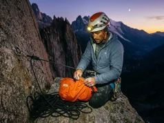 Why Staying Warm Is Only Half Your Bivouac Problem Climber in headlamp light setting up emergency bivy sack on granite ledge at dusk, alpine backdrop