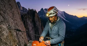 Why Staying Warm Is Only Half Your Bivouac Problem Climber in headlamp light setting up emergency bivy sack on granite ledge at dusk, alpine backdrop