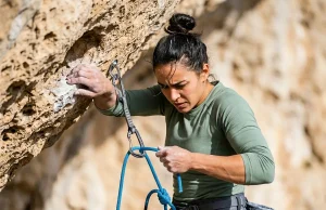 Bouldering vs Sport Climbing the Physics Behind Each Climber clipping a quickdraw on a limestone sport route illustrating bouldering vs sport climbing differences