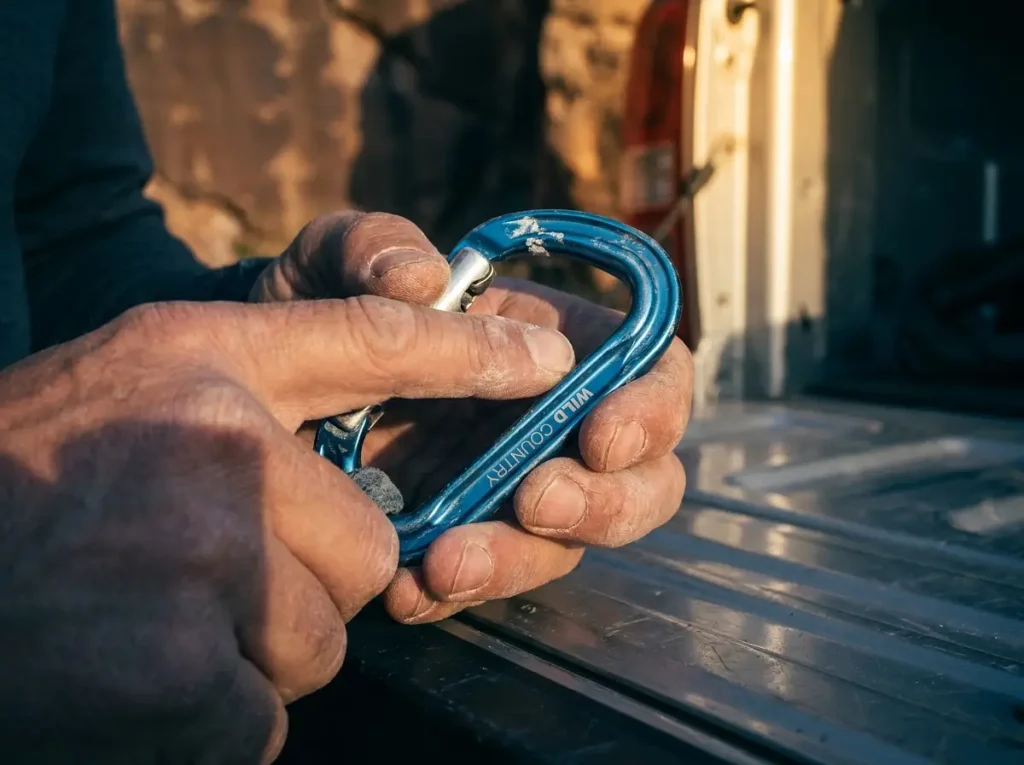 Climber testing gate action on Wild Country carabiner for wear before buying used