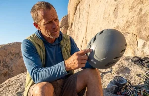 How to Inspect a Climbing Helmet Before It Fails You Climber holding a Petzl climbing helmet up to light for inspection at a granite crag