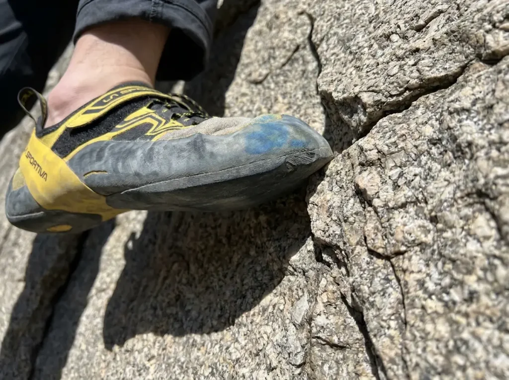 Close-up of climbing shoe toe tip on a small edge showing correct edging contact point