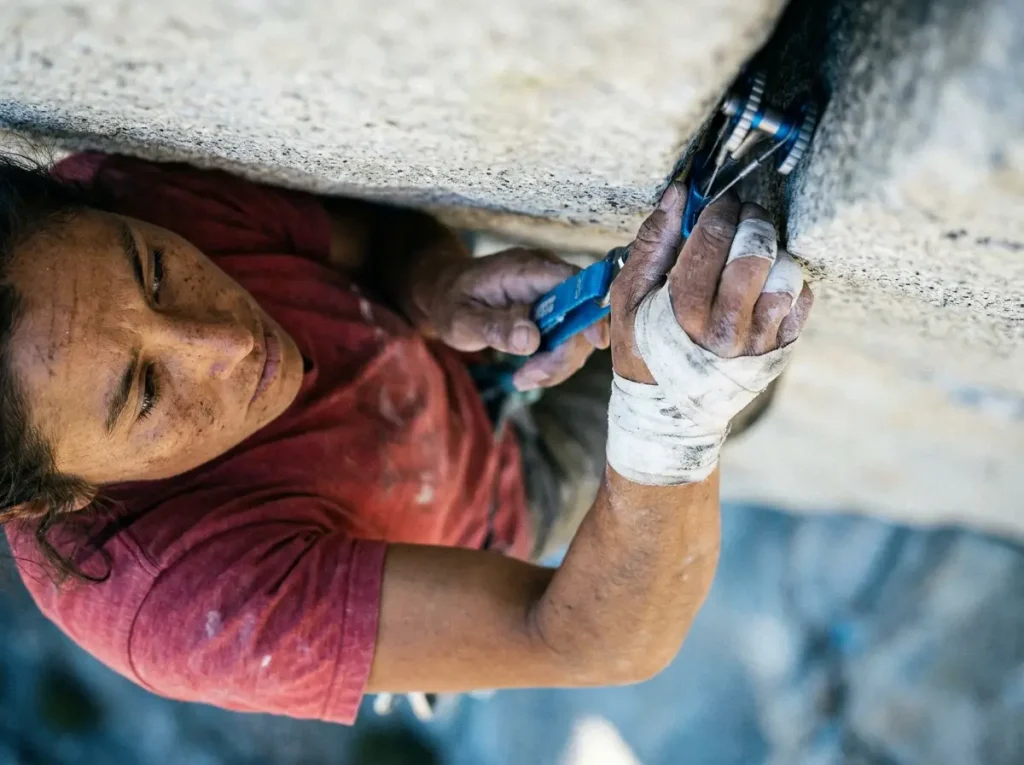 Female trad climber placing a camming device inside a granite rock crack