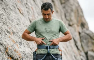 Do You Need a Full Body Harness Climbing? Climber checking full body harness fit at iliac crest before lead climbing on granite
