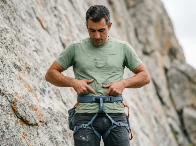 do-you-need-full-body-harness-climbing-hero Climber checking full body harness fit at iliac crest before lead climbing on granite