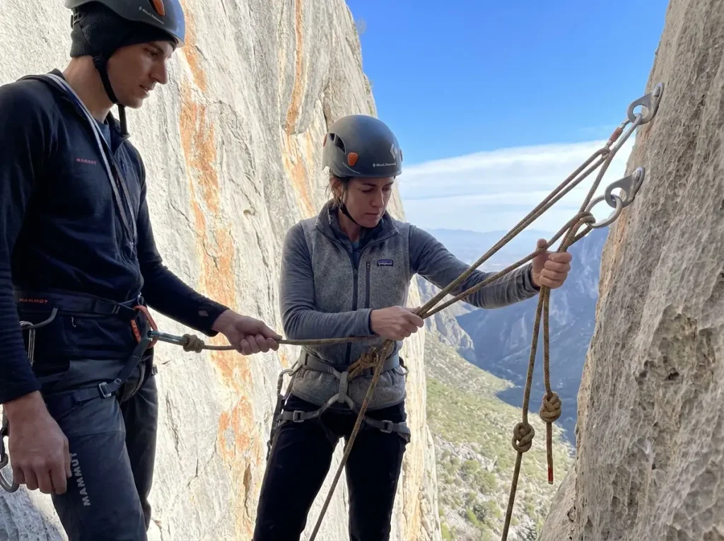 Two climbers setting up rappel on El Potrero Chico multi-pitch descent with rope ends tied
