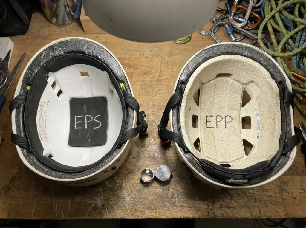 Two climbing helmets side by side with foam interiors exposed showing EPS and EPP material types