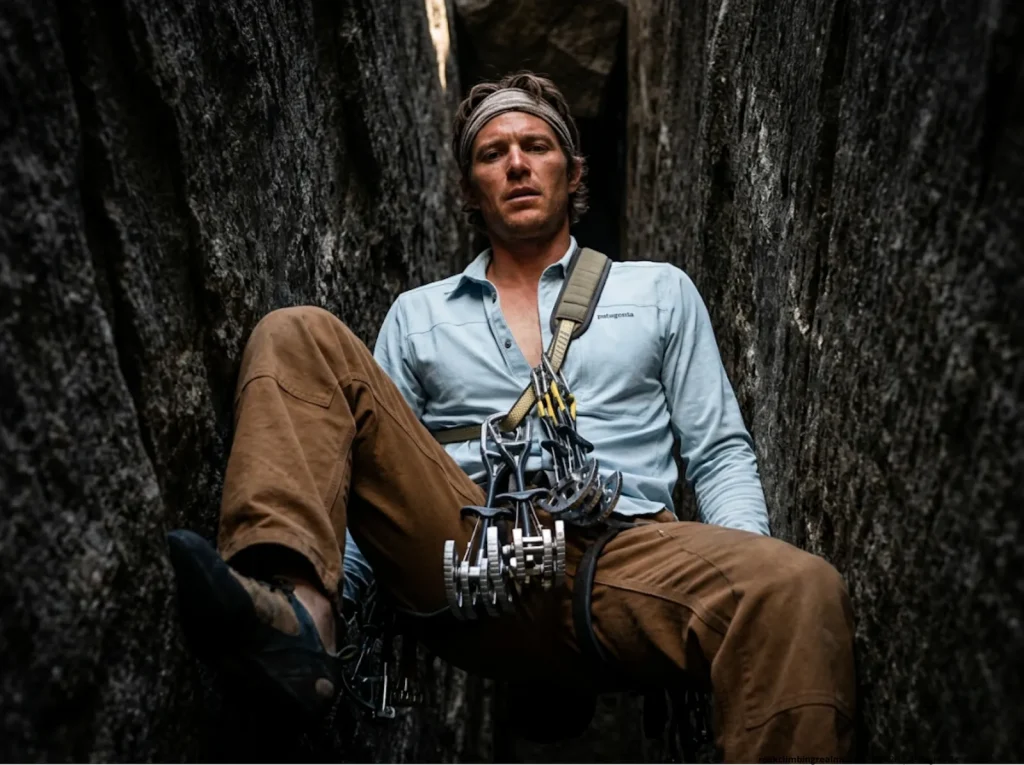 Climber in a tight chimney using a shoulder gear sling for large off-width trad climbing cams.