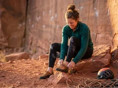 How to Stretch Tight Climbing Shoes Safely (Field-Tested) A female climber attempts how to stretch tight climbing shoes safely before a climb.