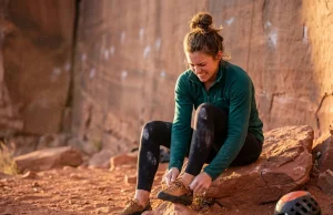 How to Stretch Tight Climbing Shoes Safely (Field-Tested) A female climber attempts how to stretch tight climbing shoes safely before a climb.
