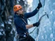 8-Week Ice Climbing Fitness Training Plan Field-Tested Ice climber executing precise wrist-driven Petzl Nomic swing on a steep WI4 blue ice pillar