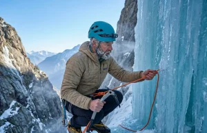 4 V-Thread Mistakes That Get Climbers Hurt Ice climber threading cord through blue ice V-thread anchor at alpine waterfall in winter