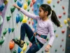 12 Indoor Climbing Games for Kids That Teach Technique Young girl placing her foot precisely on a climbing hold during an indoor kids climbing game
