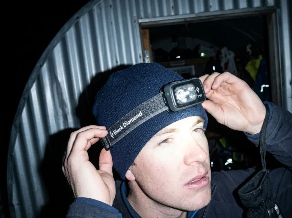 Climber pulling on a headlamp in the pre-dawn dark before Elbrus's 1 a.m. summit-day start