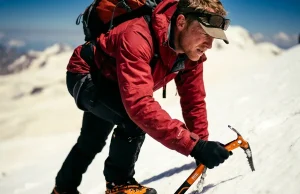 Mount Elbrus Climbing Guide — Easiest 7 Summit Reality Mountaineer performing a rest step with an ice axe on a steep snow slope on Mount Elbrus