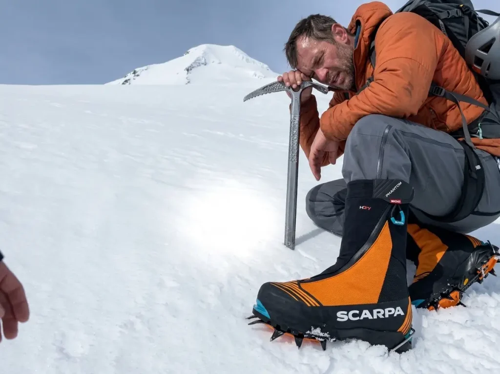 Tired climber mid-slope on Elbrus with the summit still far above showing the continuous push