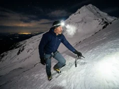4 Mount Hood Climbing Mistakes That Send for Rescue Climber ascending steep snow slope on Mount Hood South Side route at pre-dawn with headlamp and ice axe