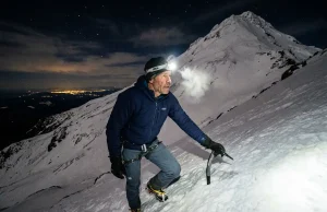 4 Mount Hood Climbing Mistakes That Send for Rescue Climber ascending steep snow slope on Mount Hood South Side route at pre-dawn with headlamp and ice axe