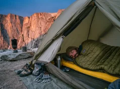 Why Sleep Is the Climbing Training You Skip Most Climber sleeping in tent at base of granite crag with climbing gear laid out beside them