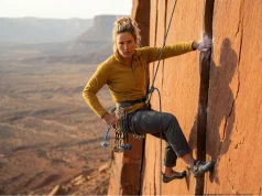 How to Rack Trad Gear So You Never Fumble a Lead Female trad climber efficiently pulling a Black Diamond cam from an organized harness loop on steep rock.