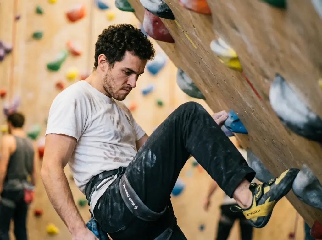 Climber with gaze directed at small foothold during foot placement on overhanging wall