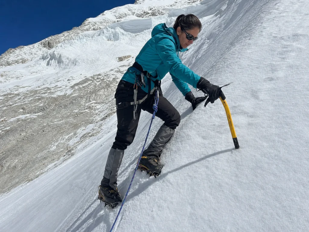 Climber front-pointing up a steep snow slope with an ice axe on Huascaran's Normal Route — Huascaran climbing difficulty