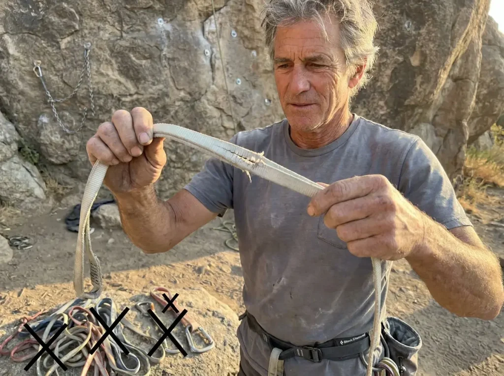 Climber bending stiff old webbing sling that crackles instead of flexing smoothly