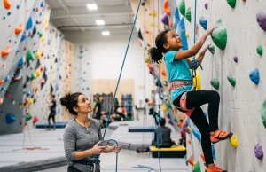 Why Most Kids Quit Climbing (And How to Prevent It) Young child climbing colorful indoor wall with parent belaying below