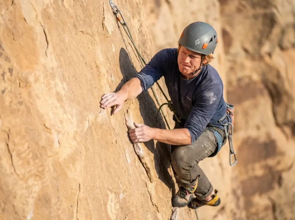 Climber struggling on an easy outdoor route gripping natural rock holds