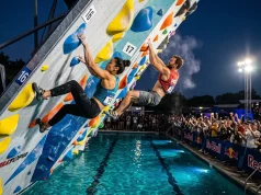 How Psicobloc Competitions Actually Work Two climbers racing side by side on overhanging psicobloc wall above deep pool