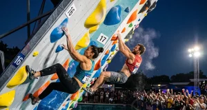 How Psicobloc Competitions Actually Work Two climbers racing side by side on overhanging psicobloc wall above deep pool