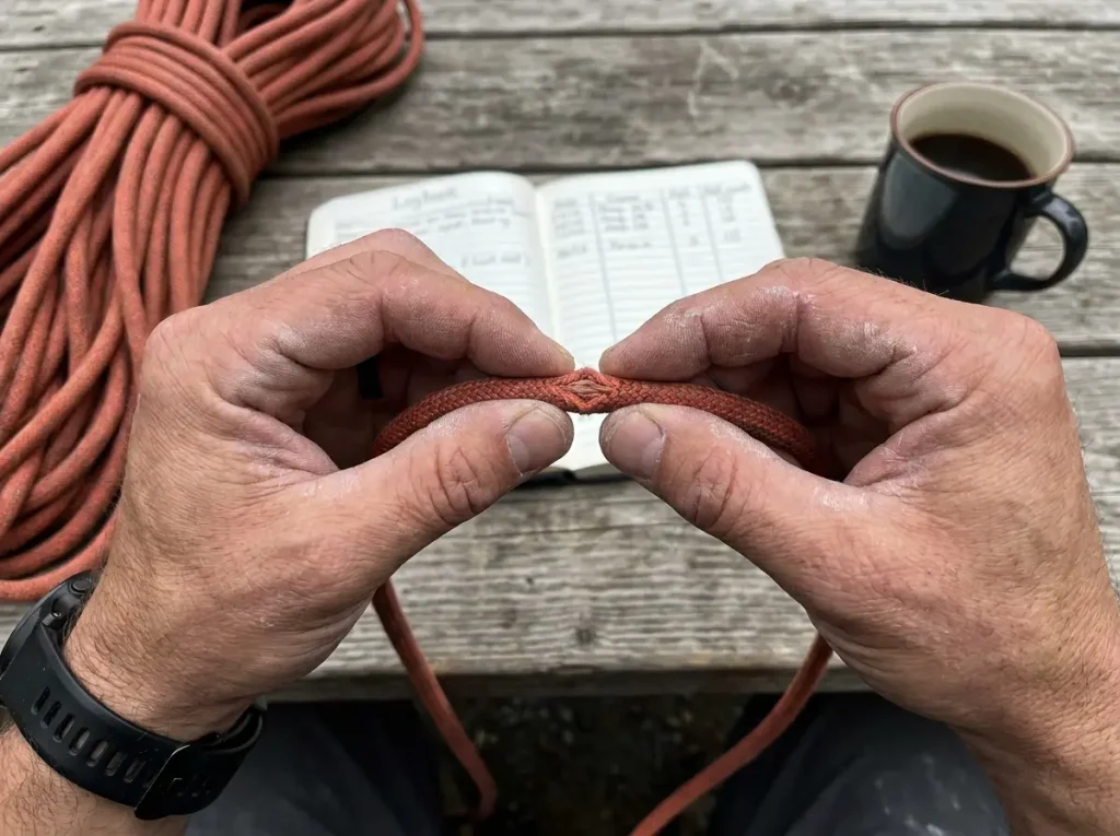 Hands performing rope pinch test to detect core damage on climbing rope