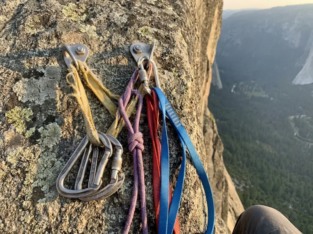 Faded old bail sling and rappel anchor webbing on cliff edge bolts