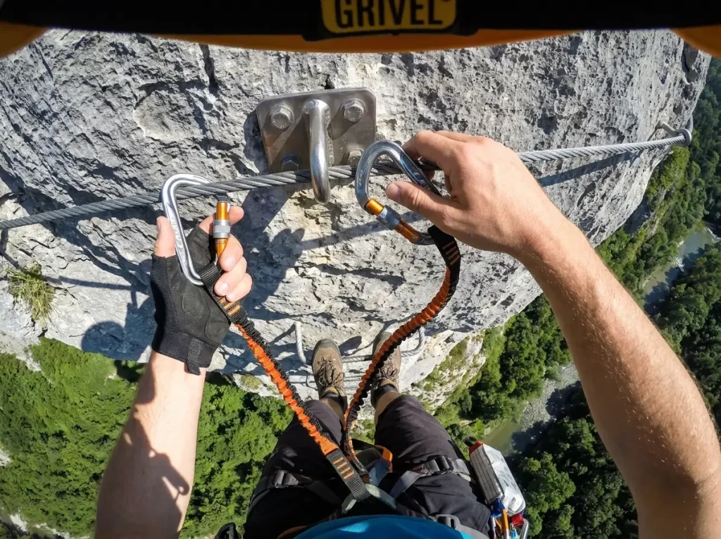 Hands demonstrating proper one-at-a-time via ferrata carabiner transition