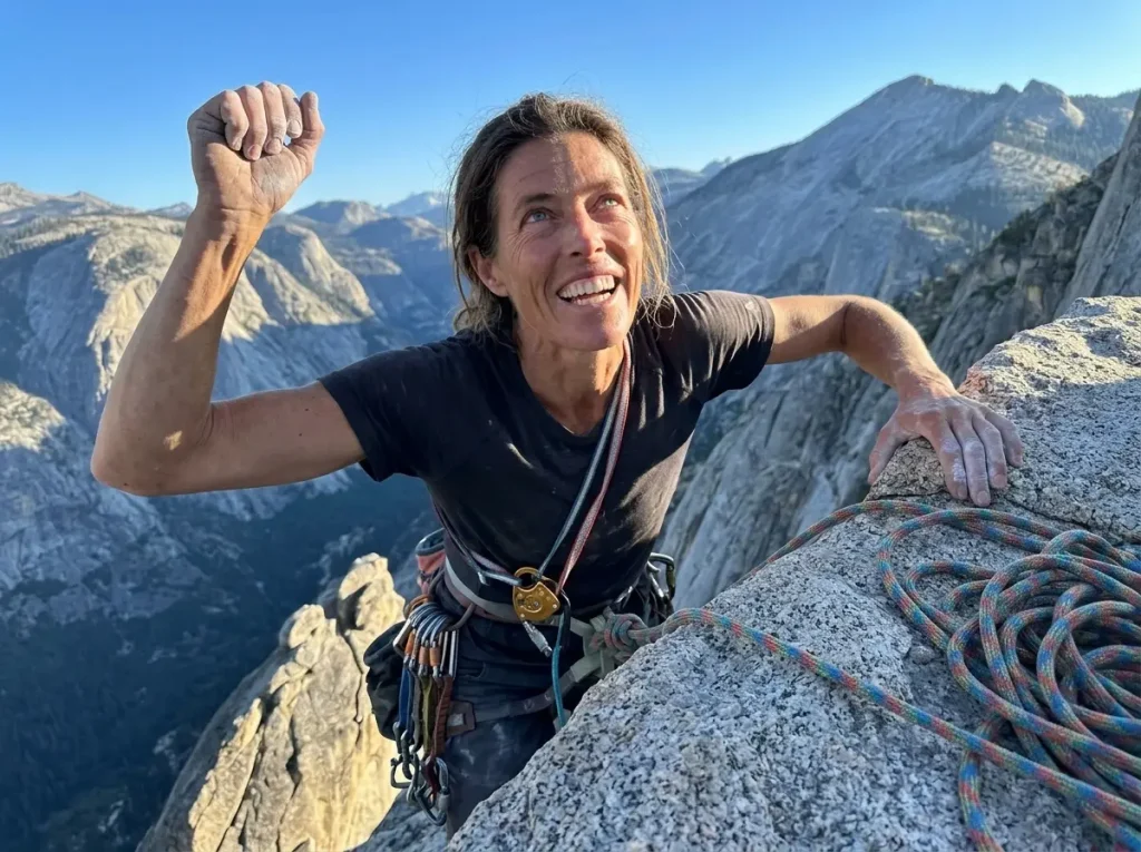 A climber topping out on a sunlit granite summit high above Yosemite Valley after a hard big-wall free climb