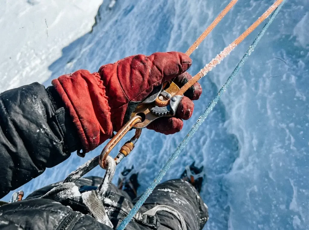 Mittened hands clipping an ascender to a fixed line, a core technical Everest prerequisite skill