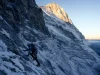 40 Eiger North Face Routes and the One to Know Roped climber small against the vast Eiger North Face at first light