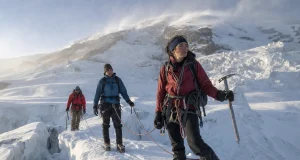 4 Mount Rainier Routes and Who Each One Is For Roped climbing team crossing a glacier on Mount Rainier at first light