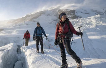 4 Mount Rainier Routes and Who Each One Is For Roped climbing team crossing a glacier on Mount Rainier at first light