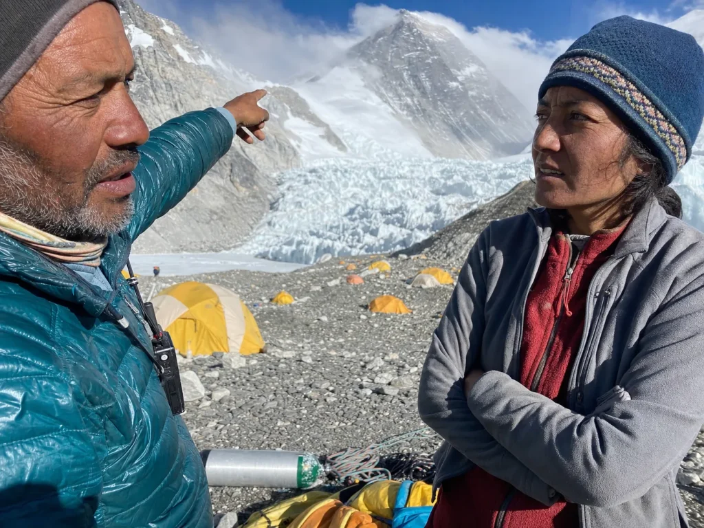 Two mountaineers studying route options at Everest Base Camp with the peak behind