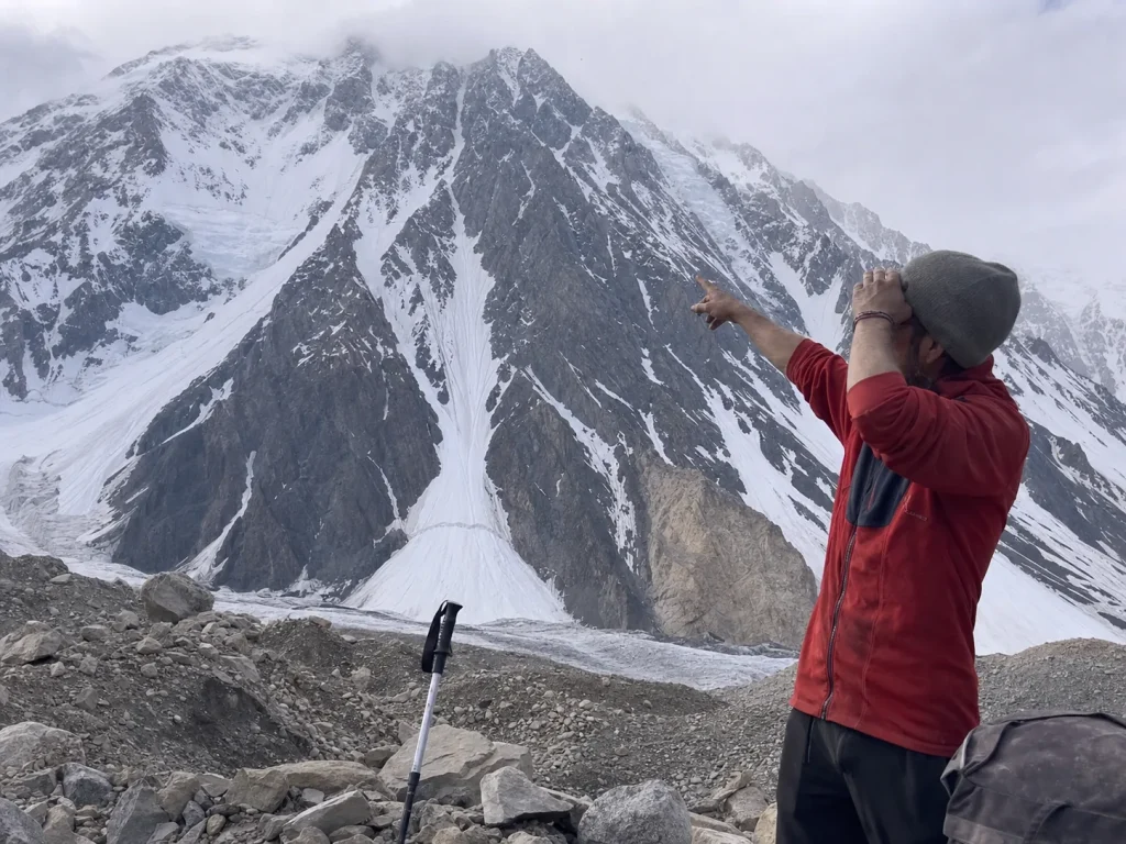 Climber at K2 Base Camp studying the mountain's south face and its route lines