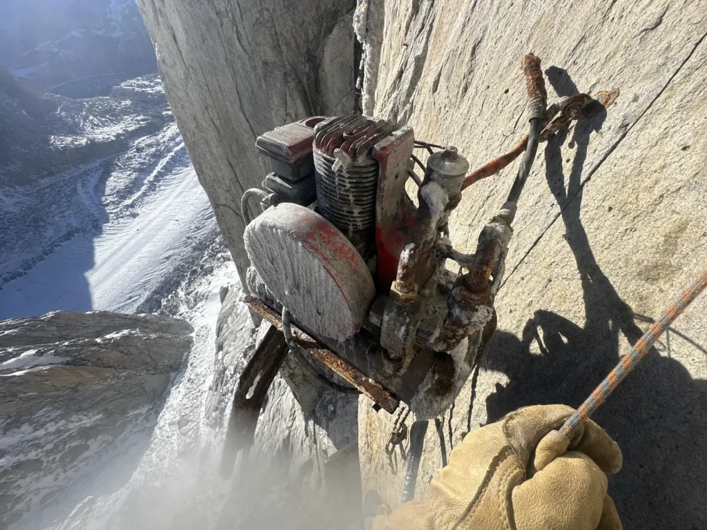 Rusted gas-powered compressor bolted to Cerro Torre's granite headwall, a landmark of the Compressor Route