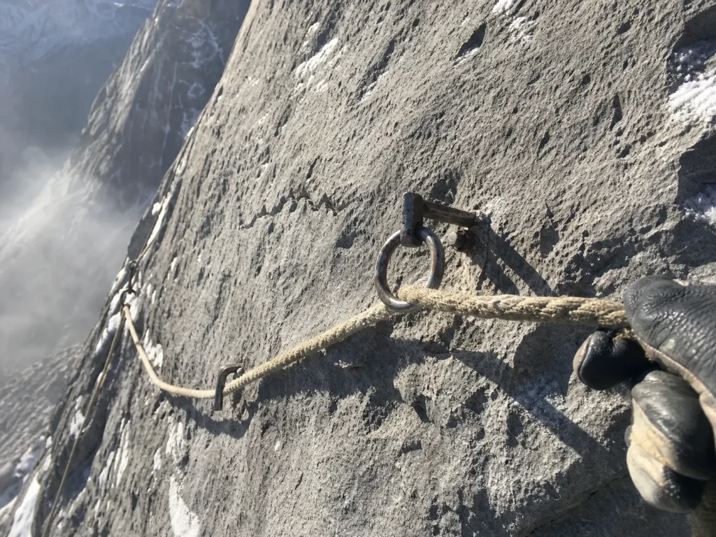 Weathered permanent fixed rope anchored across steep Eiger limestone traverse