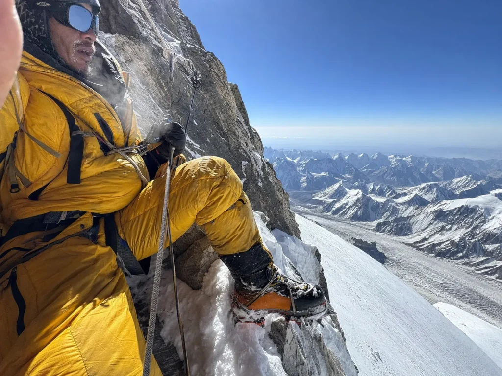 Climber ascending a fixed rope on K2's Abruzzi Spur near a steep rock step