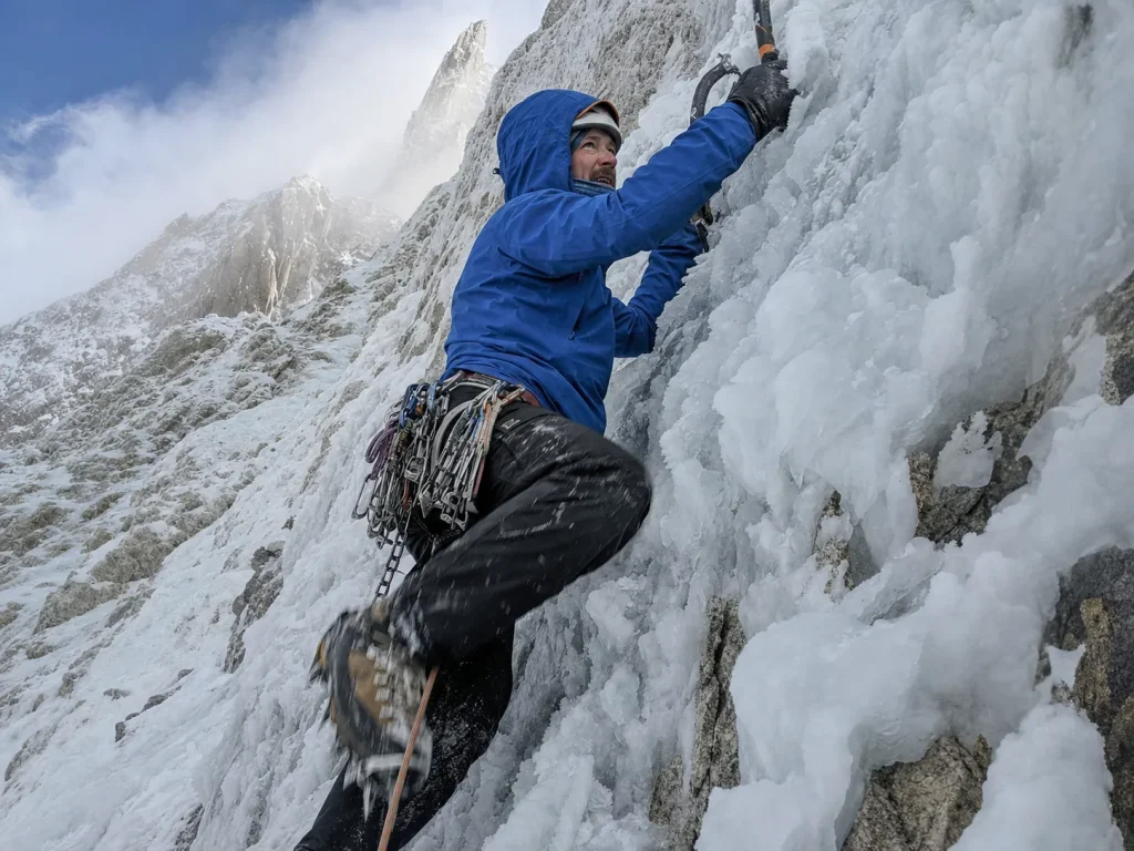 Alpinist front-pointing up a steep rime-ice runnel on Cerro Torre's West Face with two ice tools
