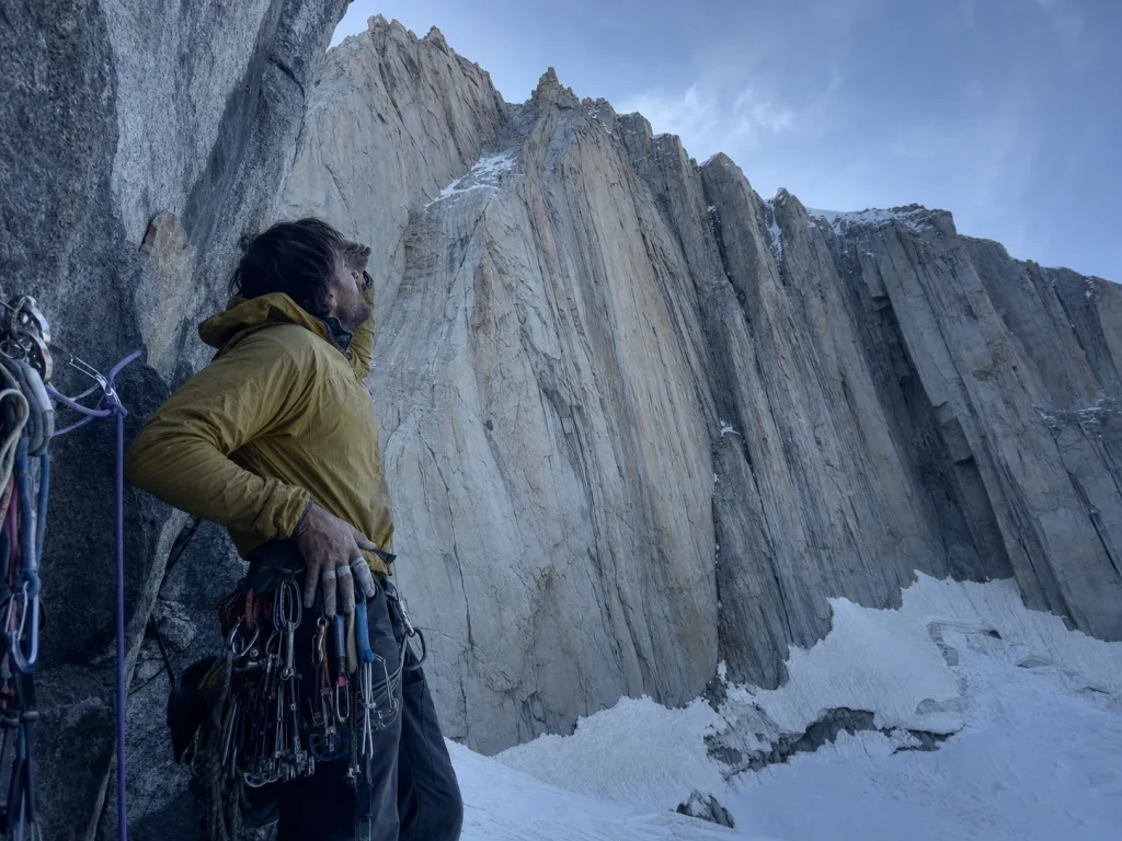 Climber assessing the crack systems and route lines on Fitz Roy's granite face