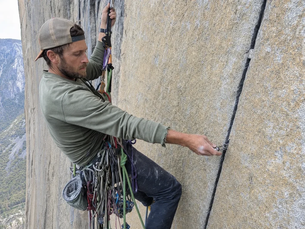 Climber aid climbing a steep granite wall on Zodiac El Capitan weighting an aider